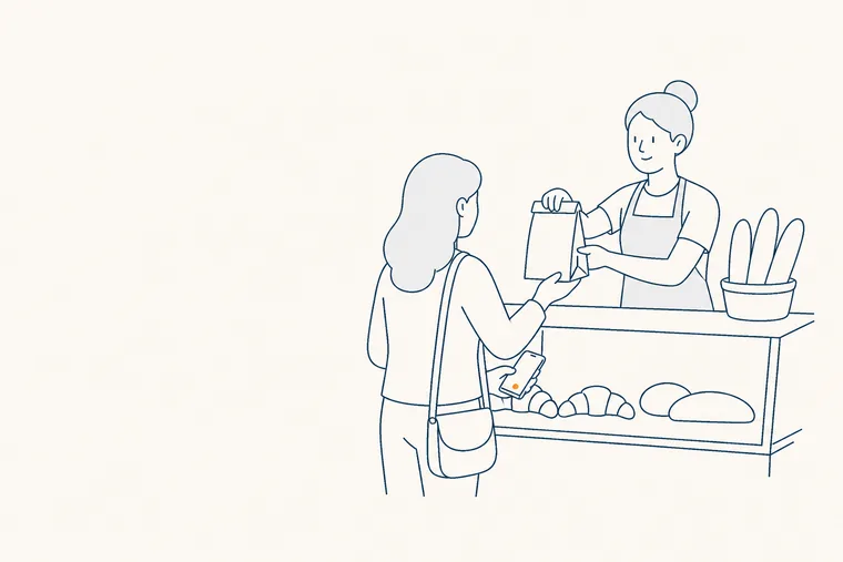 Une vendeuse tend un sachet par-dessus le comptoir d’une boulangerie.