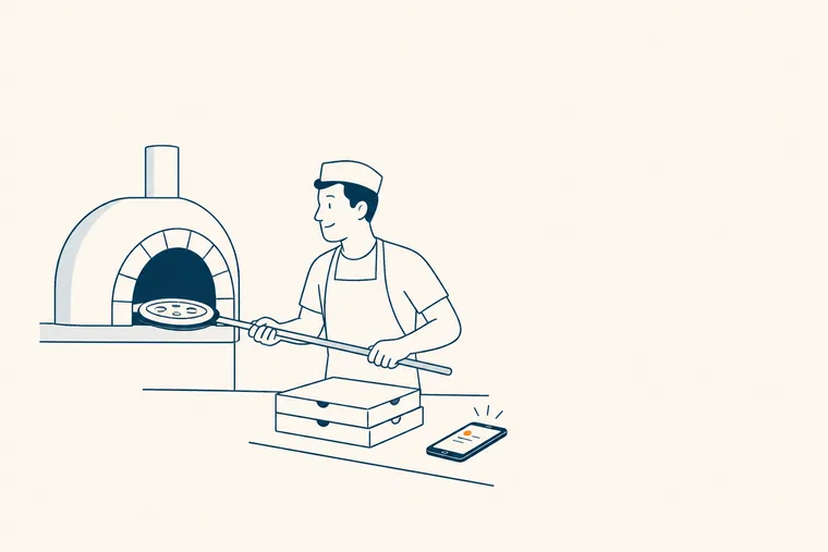Un pizzaiolo enfourne une pizza, un téléphone posé sur le comptoir reçoit une commande.